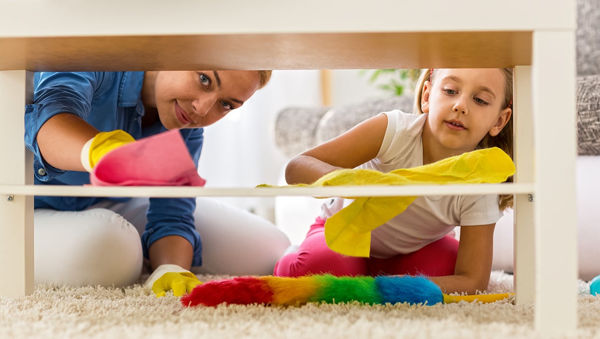 Mother and daughter cleaning dusty surface. 