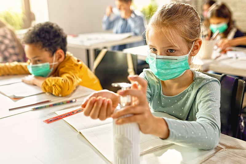 Girl in school using hand sanitizer 