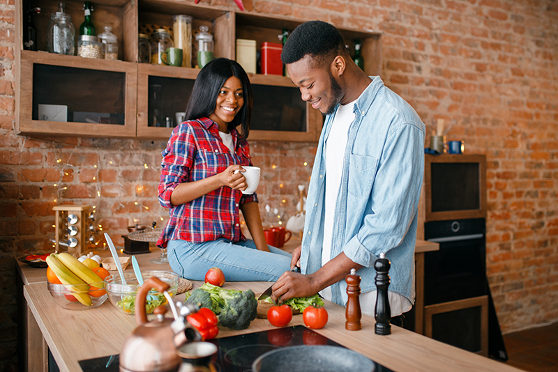 Couple in their kitchen making dinner. Cooking can cause poor IAQ indoor air quality. 