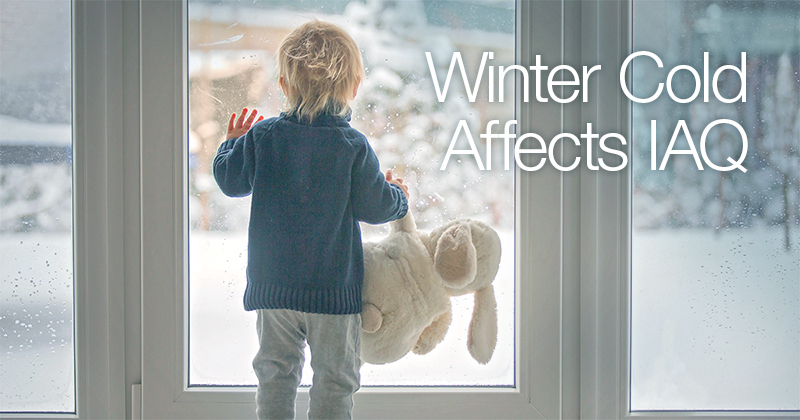 Boy indoors looking out of the backdoor during winter